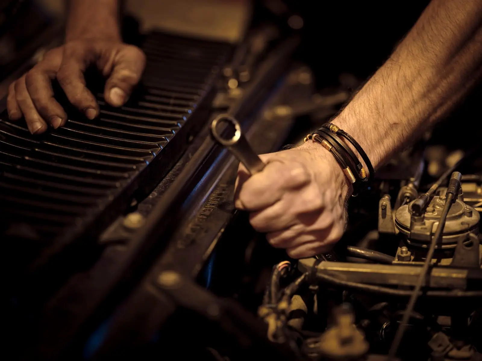 A mechanic’s hands loosening a bolt on a car engine with a wrench