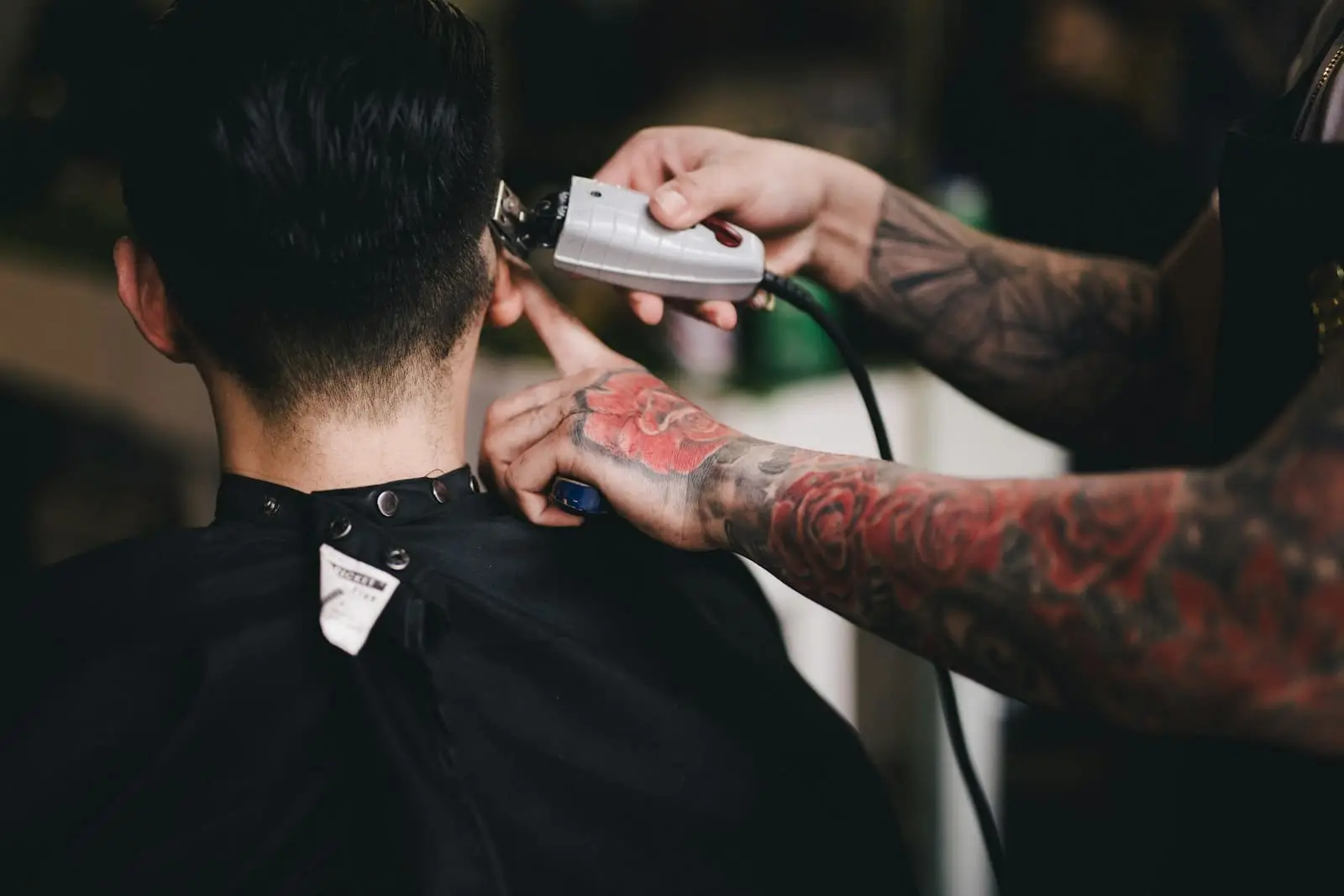 A barber trimming the back of a client’s hair with clippers