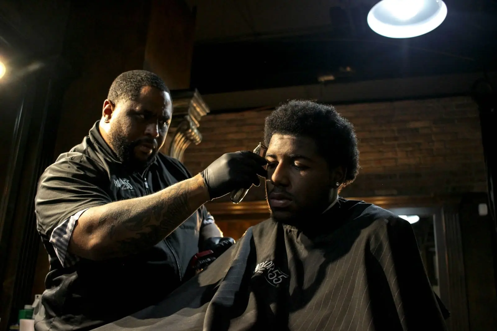 A barber finishing a haircut with comb and scissors