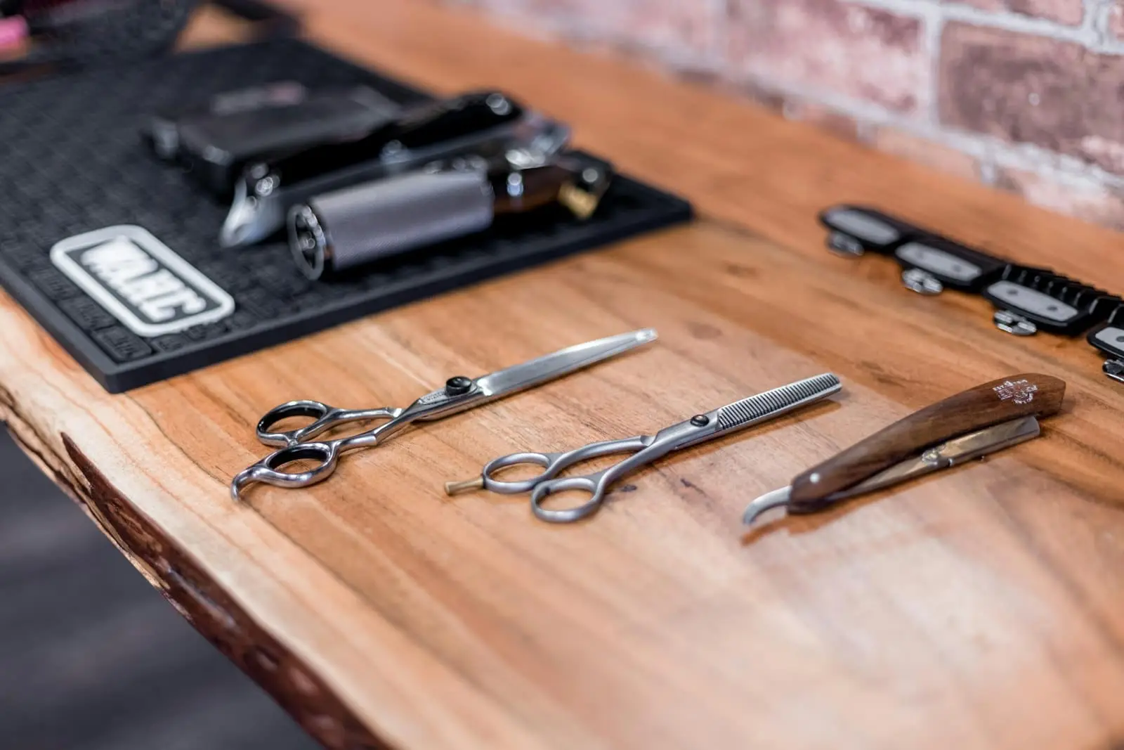 Barber scissors and a straight razor laid out on a wooden counter